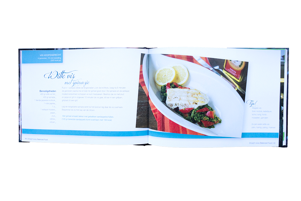 Open boekpagina van Straight away Balanced Food met recept voor witte vis met spinazie, geserveerd met groenten en citroen op een wit bord.